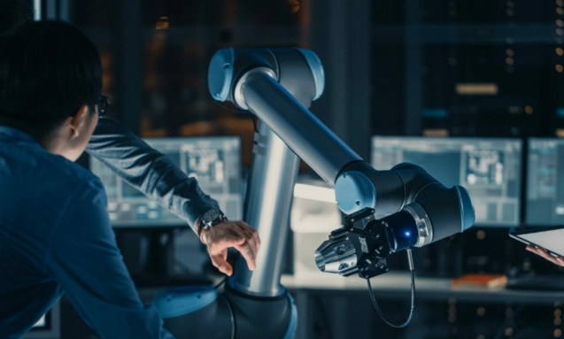 man-sits-desk-front-robot-arm